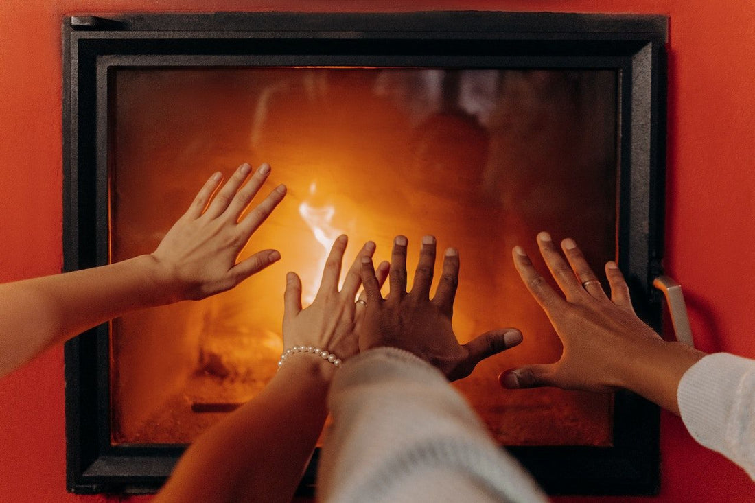 Hands warming in front of a log burner
